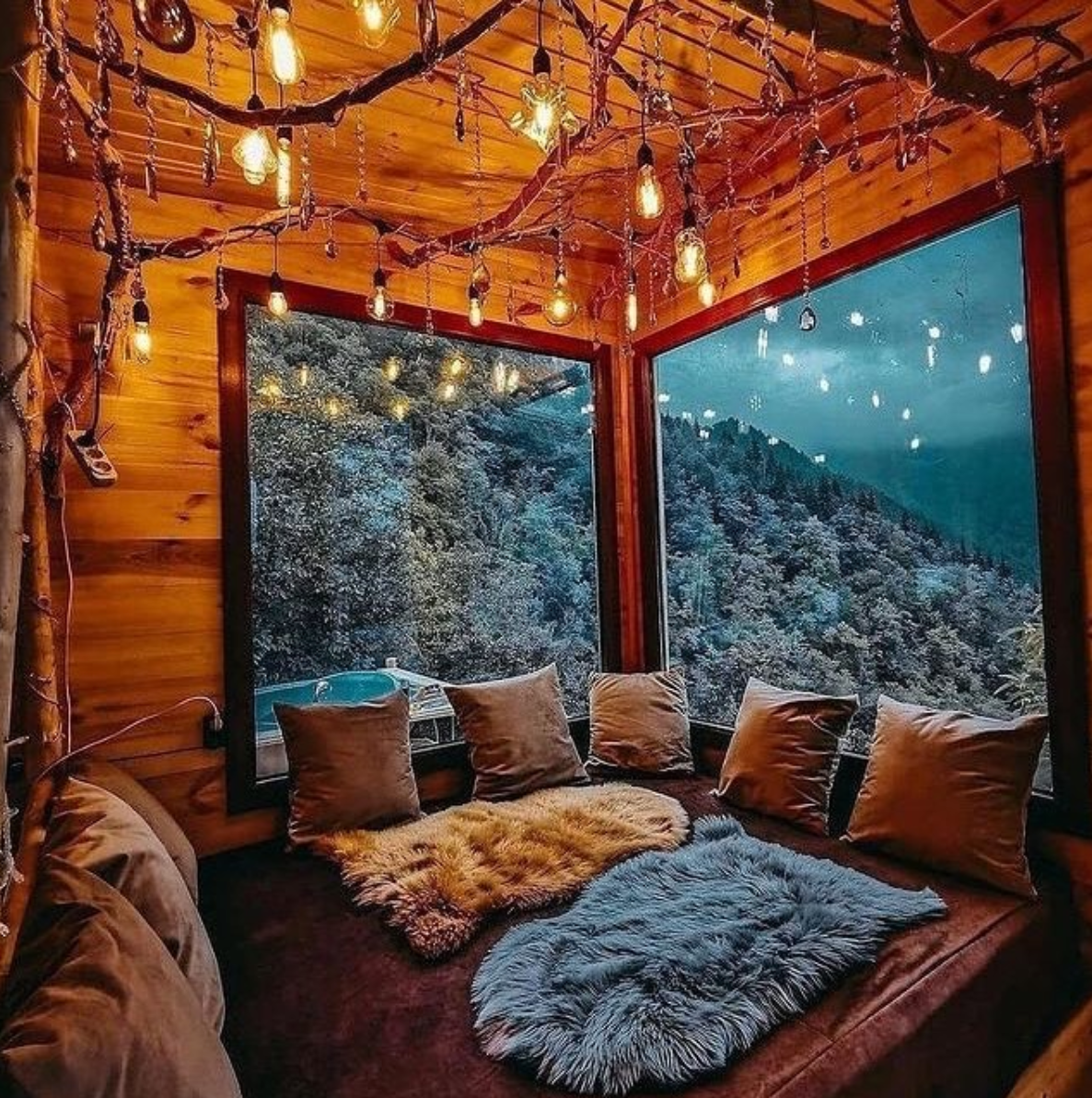 Rustic wooden bedroom adorned with string lights and thick fur throws for a decidedly friluftsliv look.