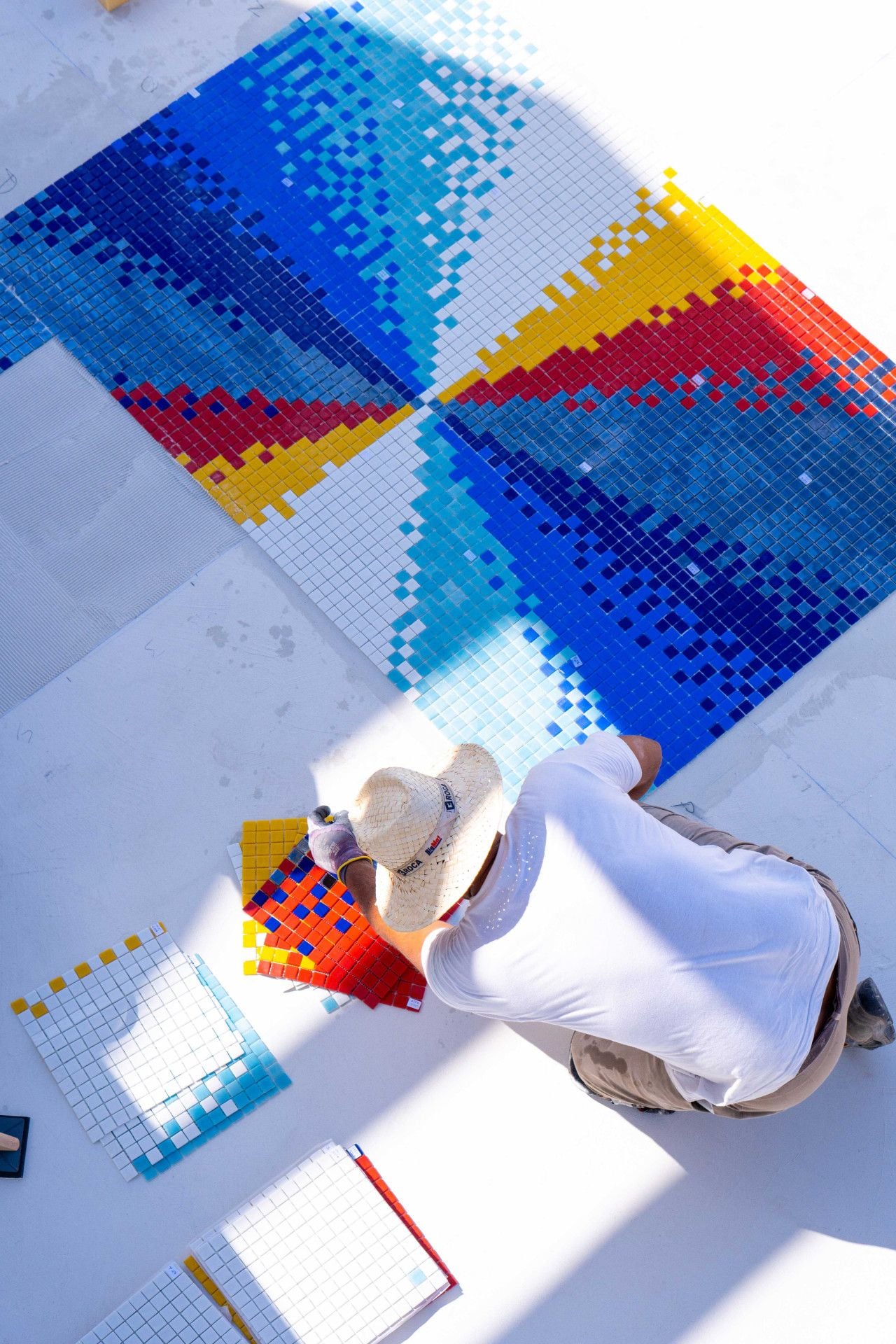 Felipe Pantone at work laying the colorful tiles on the floor of the swimming pool.