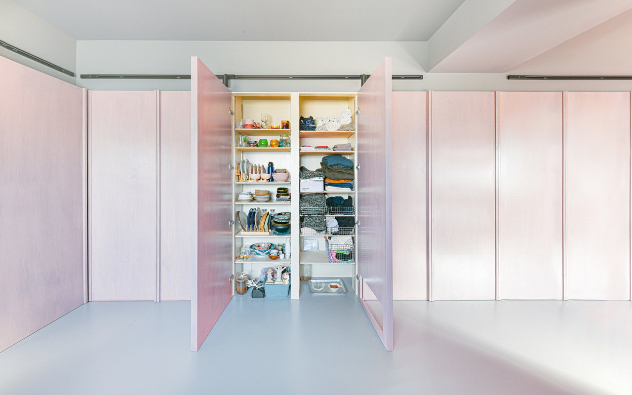 Hidden storage cabinet behind a pink wall panel in Tokyo's 404 Apartment.