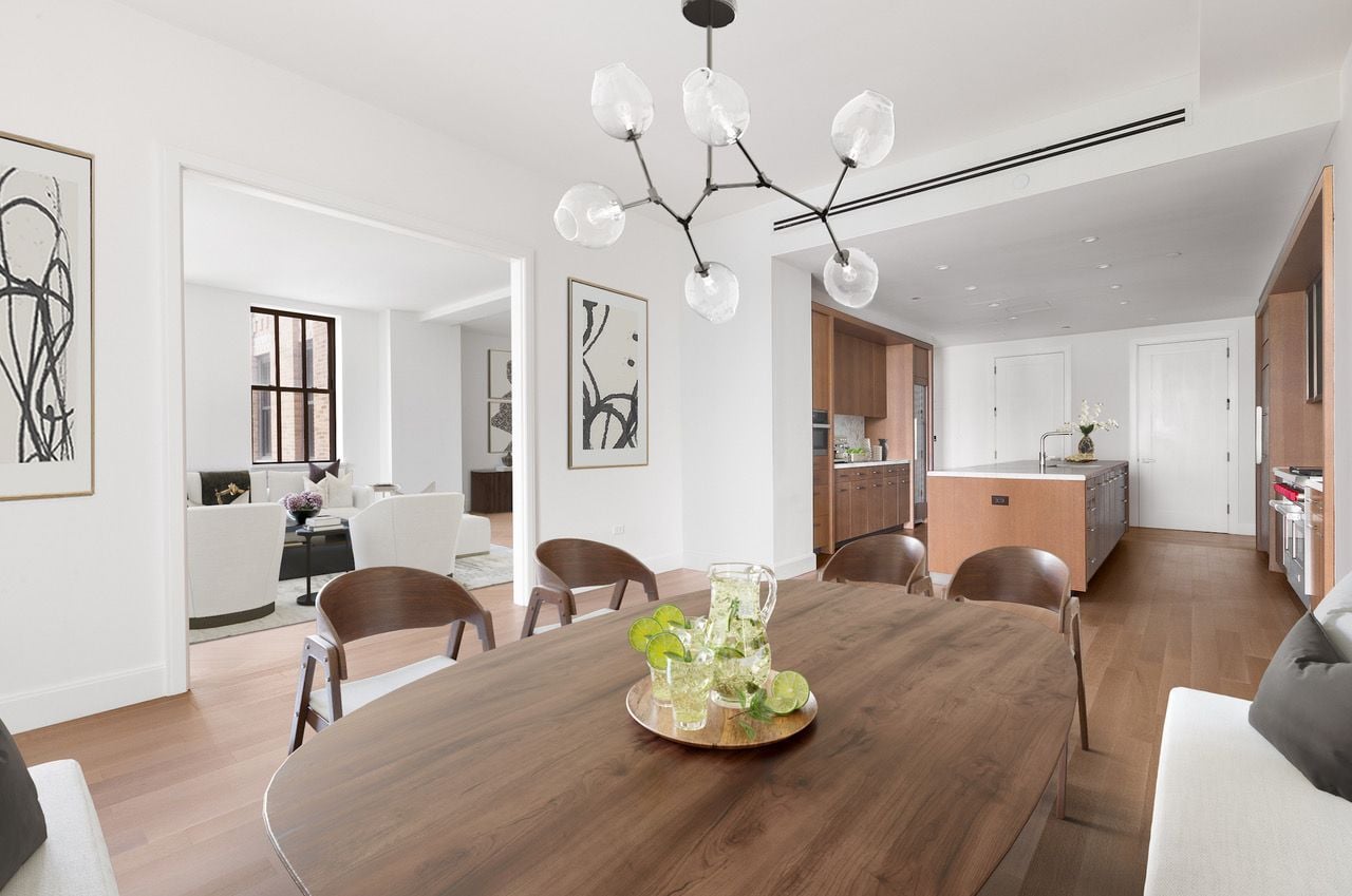 Simple, elegant dining area inside Condo 20B at the historic 100 Barclay Street, with the unit's open plan kitchen visible in the background.