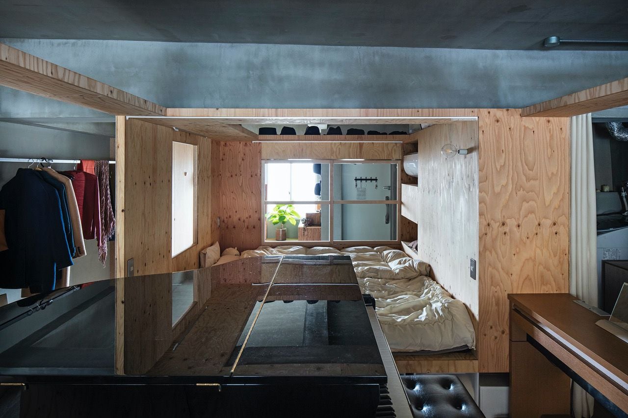 Profile view of the plywood box that houses the master bedroom in YAP's Renovated Kyoto Condo, with a large piano area visible in the foreground. 