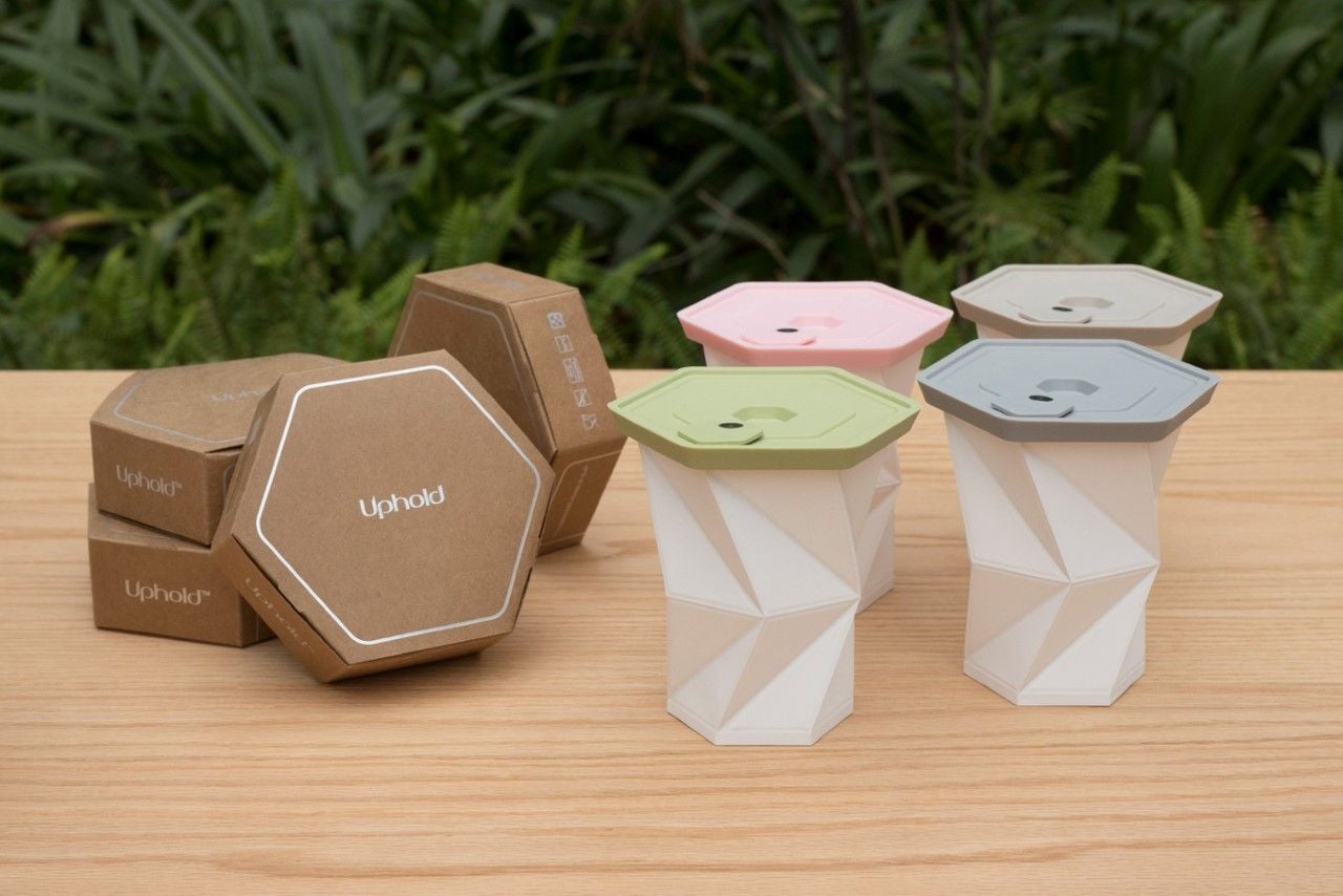 Unfolded Uphold Cups with different color lids next to their packaging. 