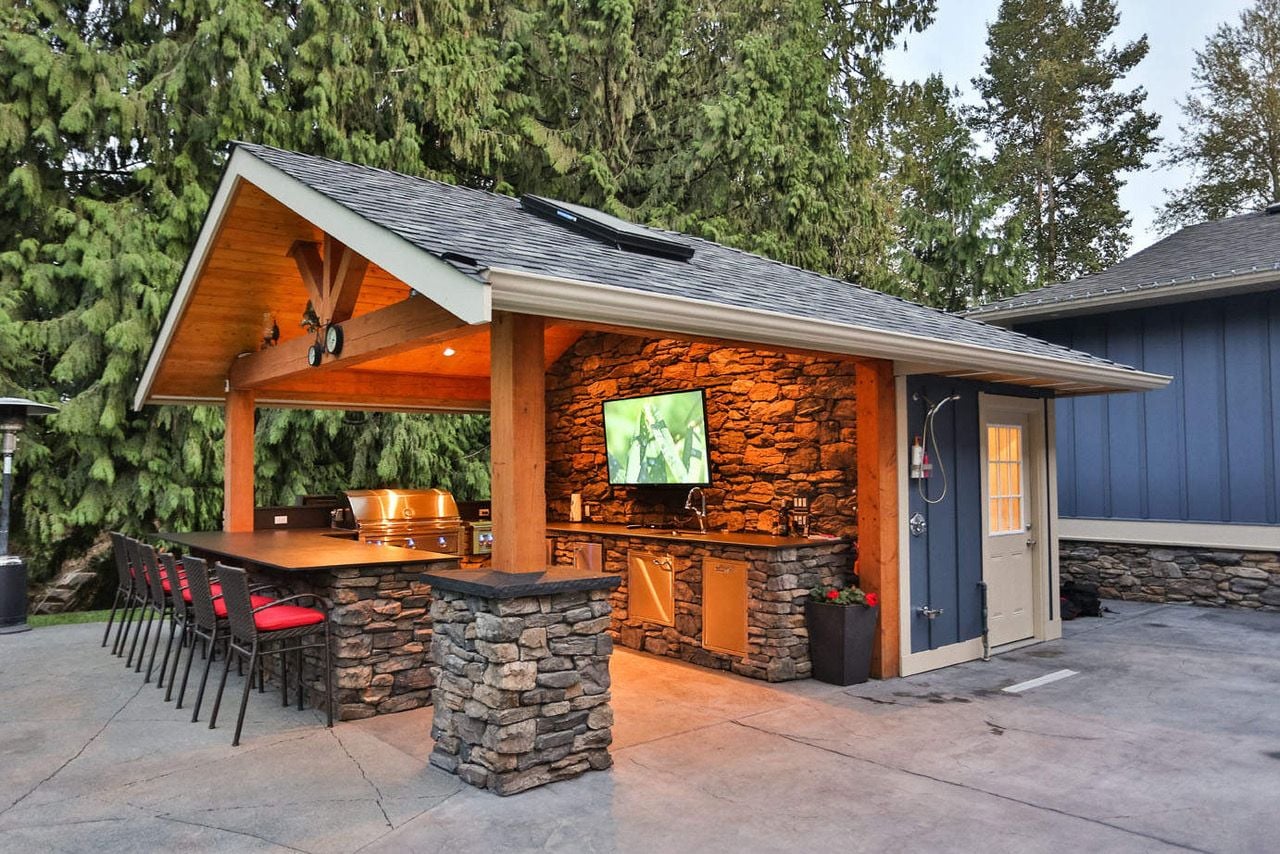 Covered outdoor kitchen space complete with a large flatscreen TV for entertaining.