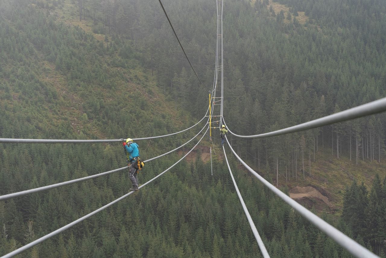 Construction workers dangle on rope as they build the death-defying Sky Bridge 721. 