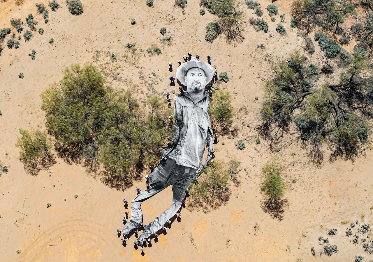 Australian farmers and indigenous peoples carry a massive portrait of sixth-generation farmer Wayne Smith through the desert as part of French artist JR's 