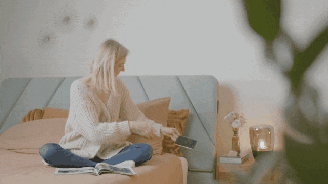 Girl charges her phone using the AirTulip Sleep's wireless smartphone charger.
