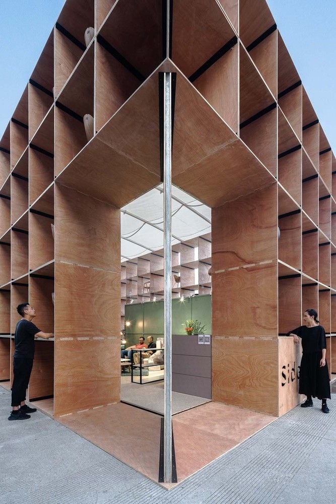 Large corner openings in the pavilion's perforated plywood facade give passerby a good look at the stylish furnishings within.