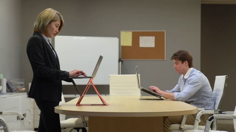 Two people hard at work using the MOFT Z Sit-Stand Desk in two completely different ways. 