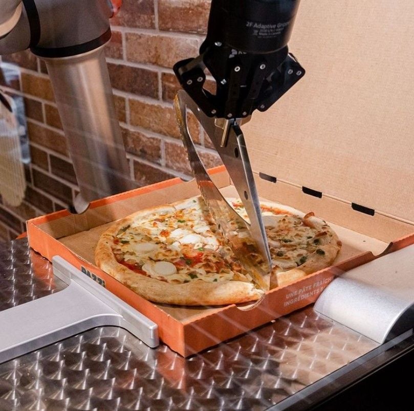 Pazzi robot chef slices up a finished pizza inside the box.