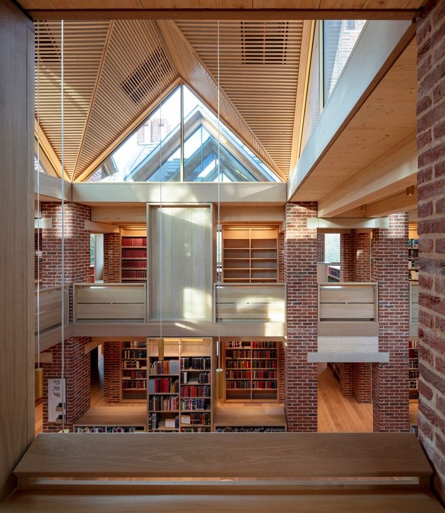 Expansive triangular windows offset the brick and wooden textures inside the New Library at Magdalene College.