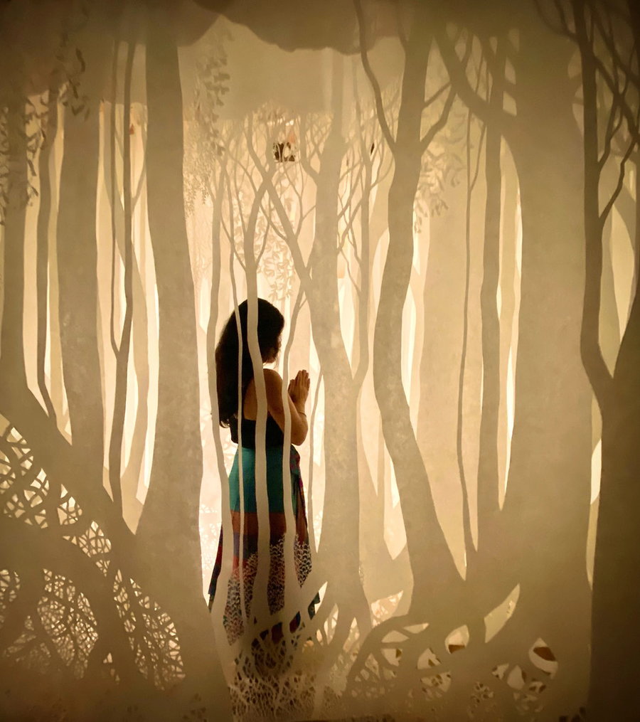 Woman wanders through a life-size paper forest by artist Ayumi Shibata.