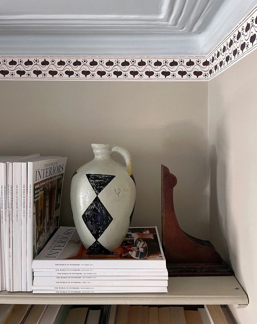 Tasteful wallpaper border wraps around an elegant bookcase display. 