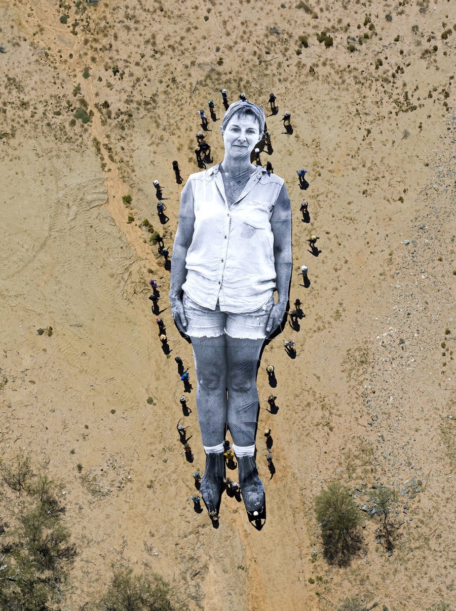 Australian farmers and indigenous peoples carry a massive portrait of orchardist Rachel Strachan through the desert as part of French artist JR's 