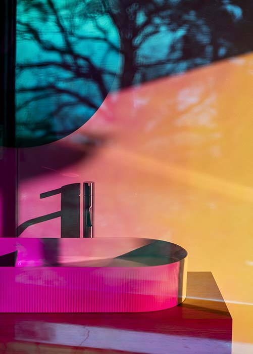 A large double wash basin featured in the new SONAR collection shines an alluring pink thanks to the refracted light from nearby panels. 