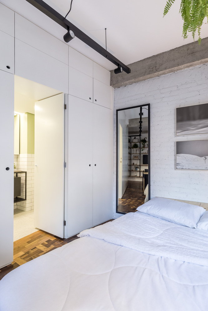 A cleverly disguised entrance to the apartment's bathroom sits right next the bed along the main storage wall.