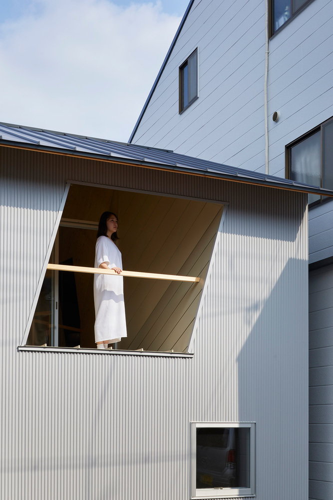 Woman gazes out the upper level balcony of the Alphaville Architects-designed 24-mm plywood tiny house in Kyoto.