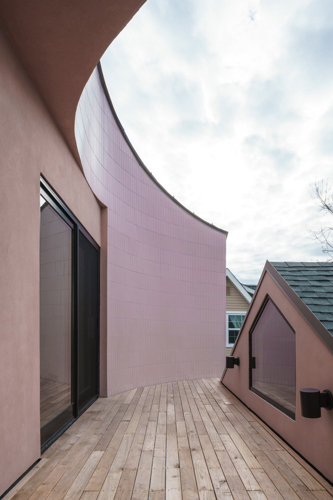 Wooden outdoor terrace pairs nicely with the House on House addition's curving pink exterior.