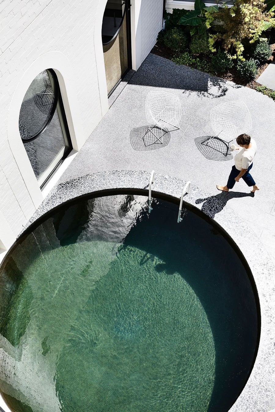 Person walks around the Caroline House's circular outdoor swimming pool.