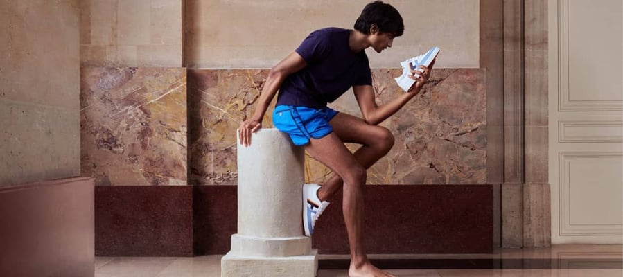 Man strikes a statue-like pose while admiring athletic shows inside Hermès' new pop-up gym space.