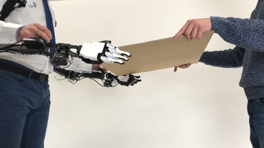 Person uses the University of Tokyo's ISL robotic arms to hand something over to another person.