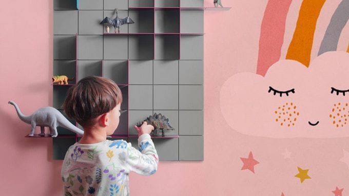 Little boy places his favorite toys on a sleek gray and pink KUR!O shelving system. 