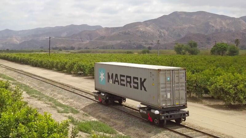 Parallel Systems' electric freight train modules transport a Maersk shipping container along a track.