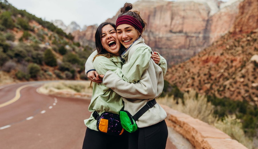 Two young girls beam with joy wearing their upcycled Rareform fanny packs. 