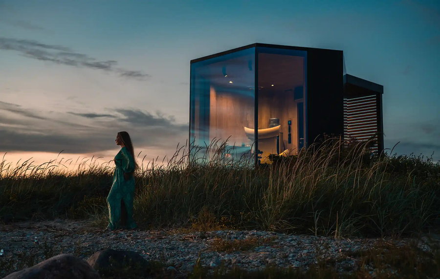 Woman stands outside her Muuw prefab work pod as the sun sets.