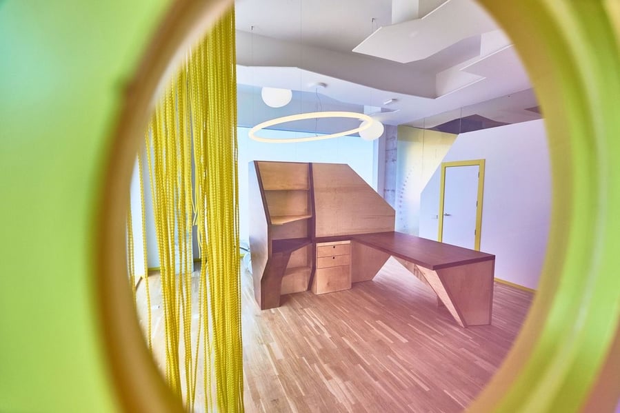 A geometric workstation inside the colorful Form of Care clinic, as seen through a peephole.