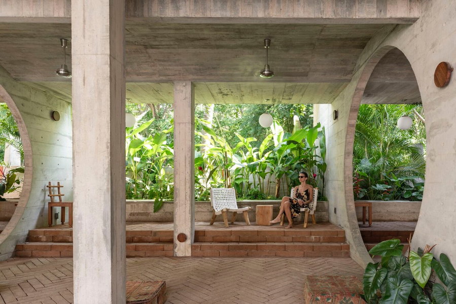 Woman lounges on a chair inside Mexico's Casa TO, with a gorgeous sea of greenery lurking just behind her. 
