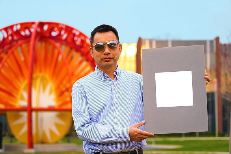 Purdue Professor Xiulin Ruan holds up a square of ultra-white paint his research team recently found could help cool the entire planet. 