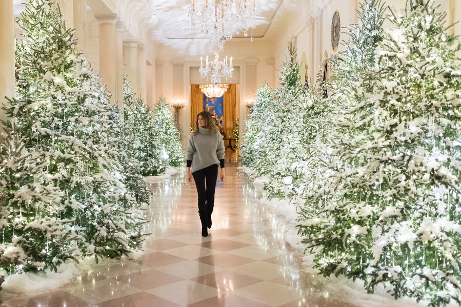 First Lady Melania Trump strolls through a traditionally-decorated White House corridor at Christmas time. 