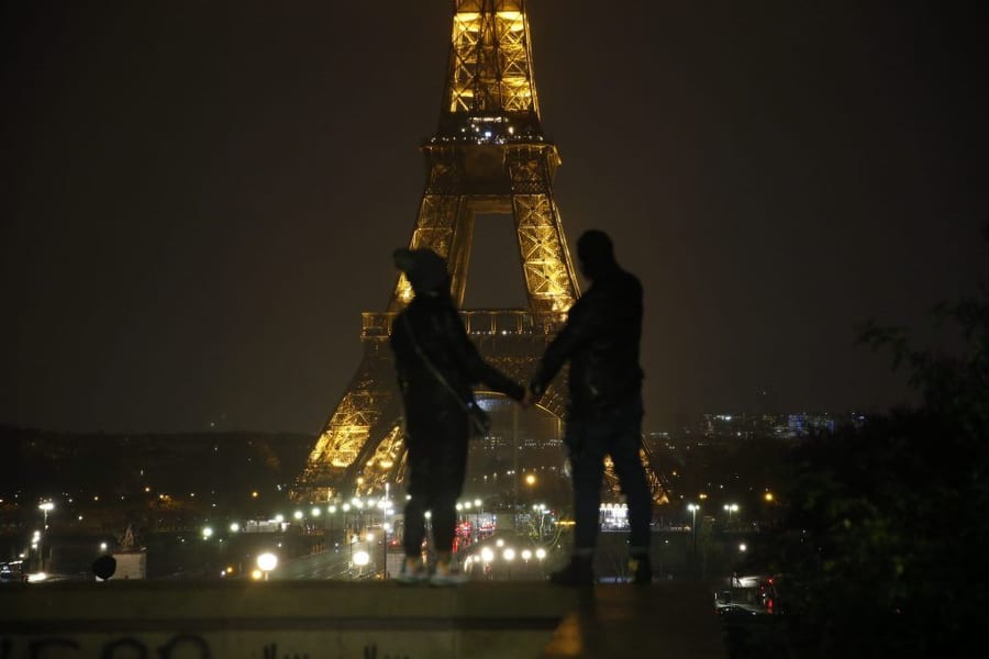Couple spends time under the Eiffel Tower at night.