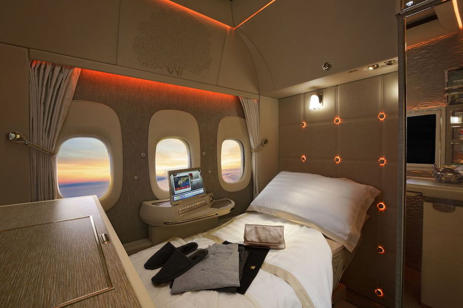Luxurious private first-class suite onboard an Emirates flight, complete with a full-length bed.