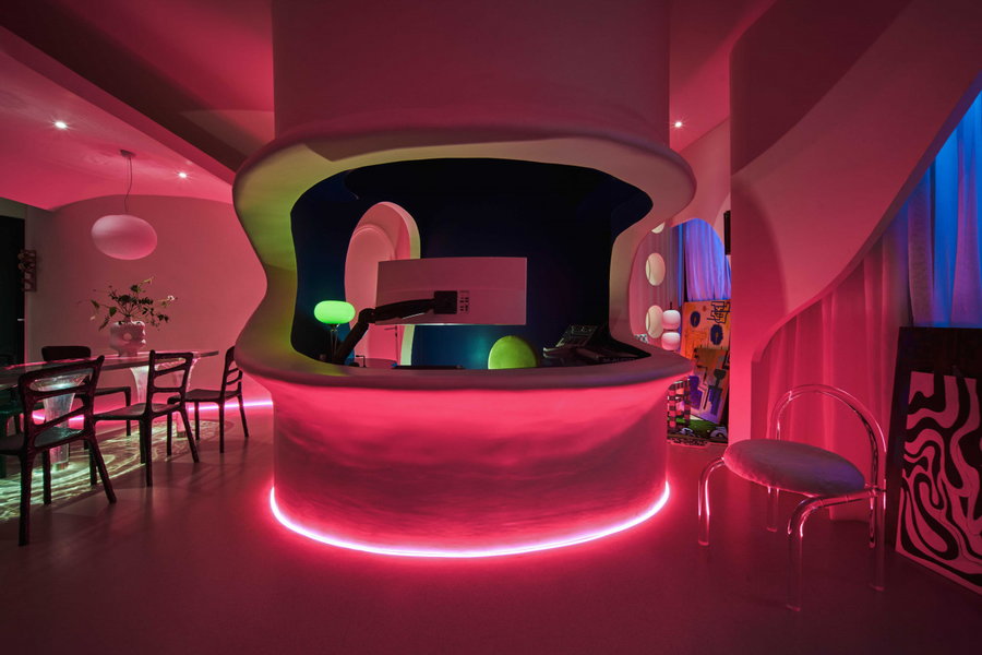 The Dreamscape apartment's main living space is lit up by brilliant neon pink floor lights.
