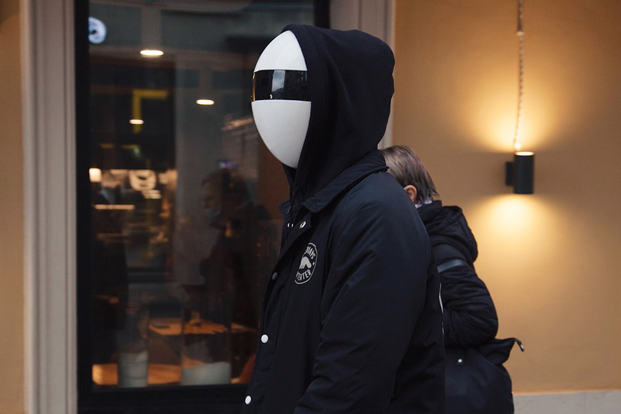 Person wears their super-conspicuous Blanc Full-Face Modular Mask under a hoodie.