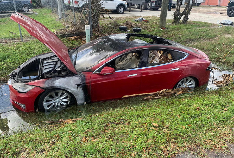 Burnt-out Tesla EV sits abandoned and inundated with water in the aftermath of Hurricane Ian.