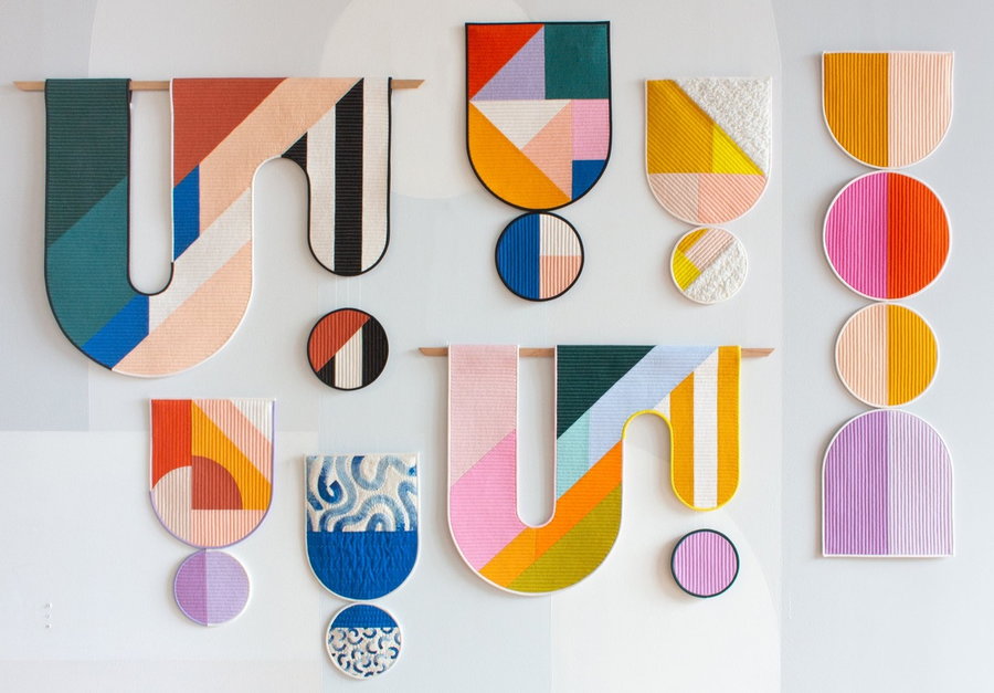 Wall space covered in a color block wall hangings by Emily Van Hoff.