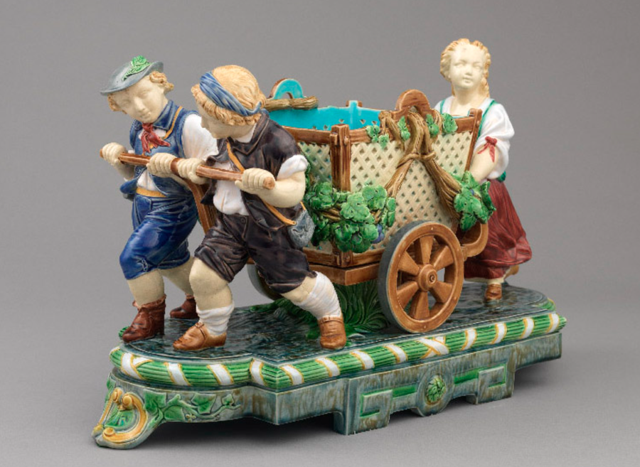 Ornate majolica pottery of traditionally dressed German folk pushing a wheelbarrow, featured in Dr. Susan Weber's 