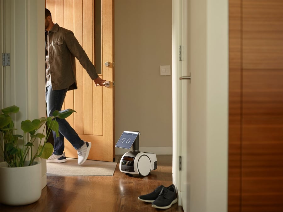 Man leaves his house for the day while his Amazon Astro robot assistant stands at the door.