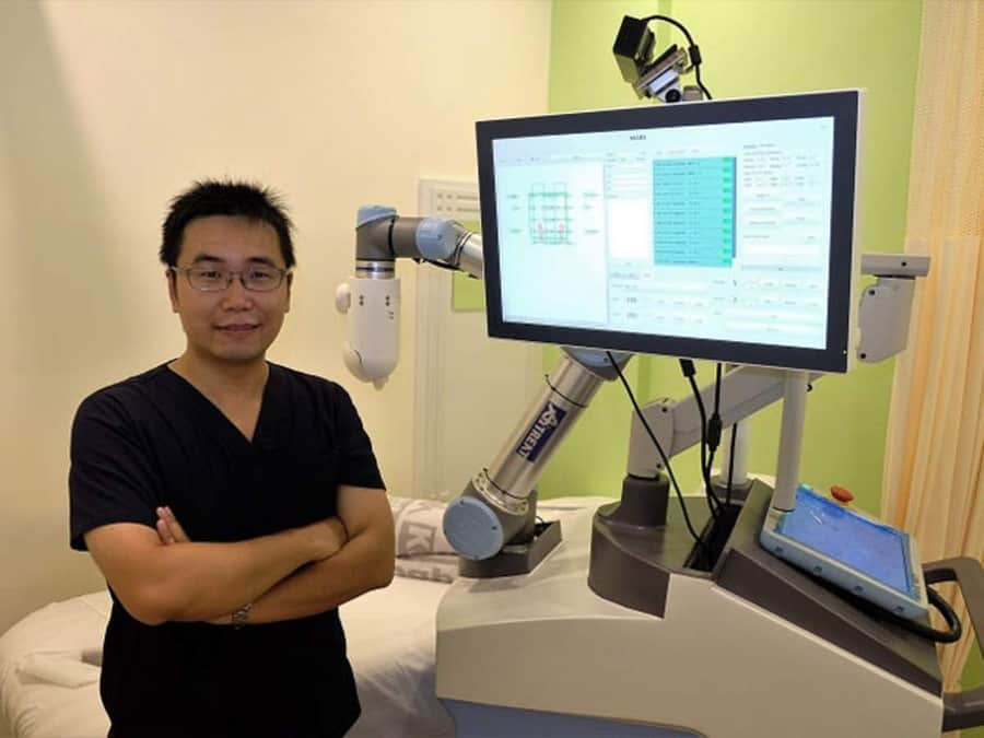 Dr. Albert Zhang poses proudly alongside his EMMA robotic masseuse. 