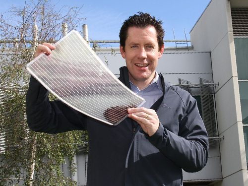 Researcher proudly displays a large sheet of flexible solar concentrating material.