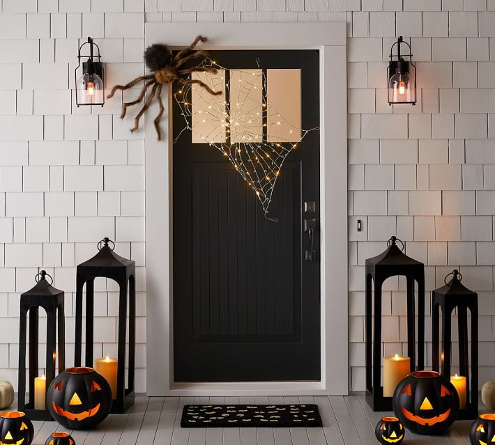 Creepy spiders, jeering jack-o-lanterns, and elegant brass candle holders from Poterry Barn's Halloween collection help make this doorstep as spooky as can be. 