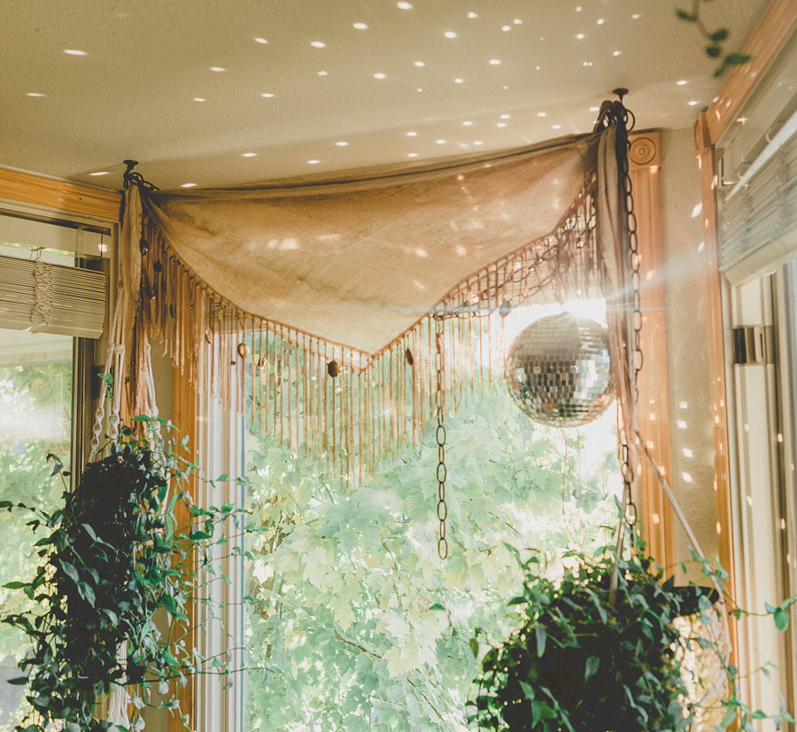 Disco ball hangs near an apartment window to flood the space with reflective light. 