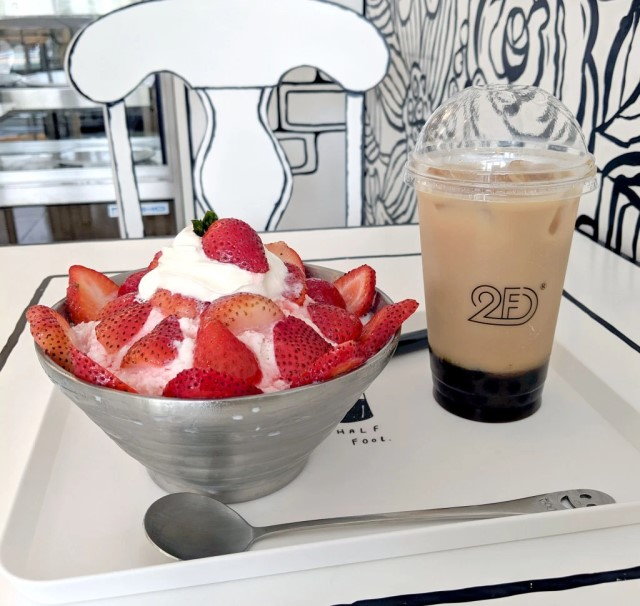 Colorful yogurt and coffee on a black and white tray inside Japan's cartoonish 2D café.