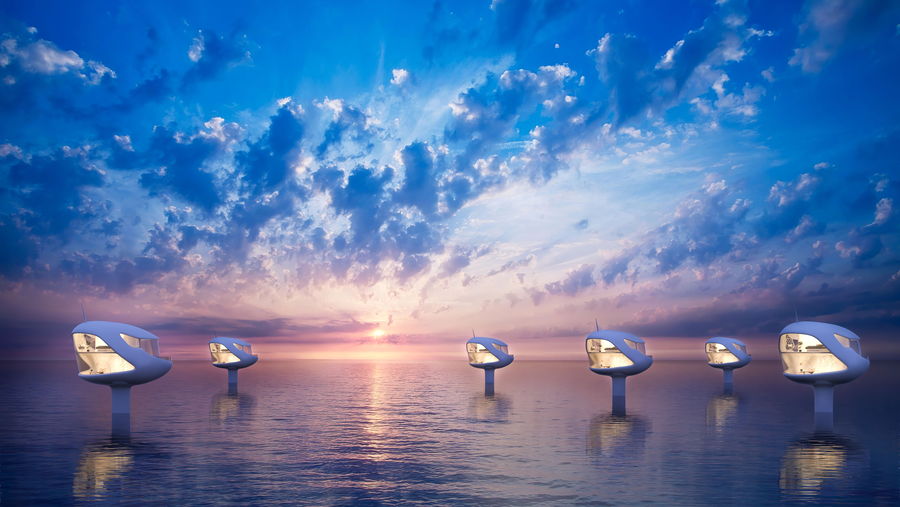 Ocean Builders' futuristic SeaPods glow above the surface of the water at sunset. 