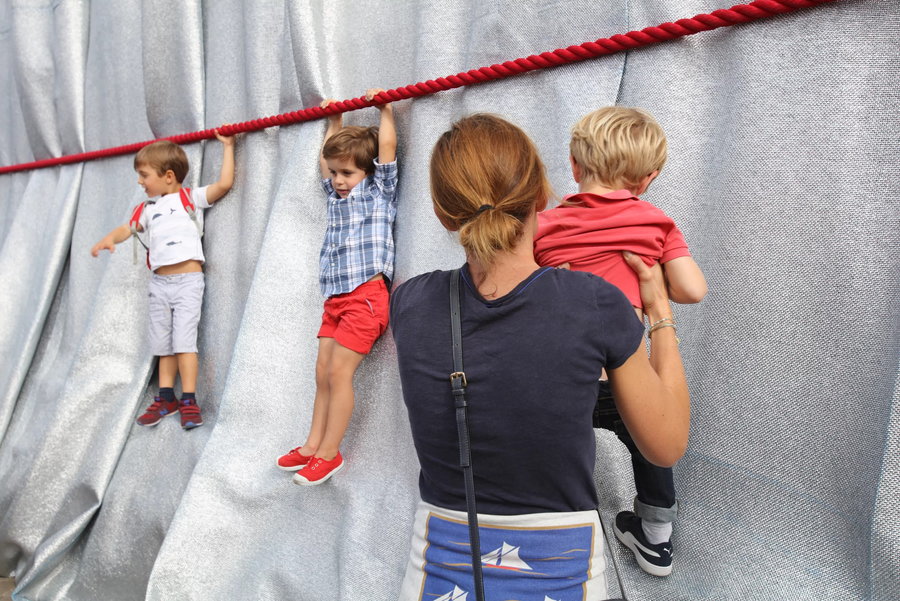 Kids hang from the bright red ropes wrapped around Paris' Arc de Triomphe.