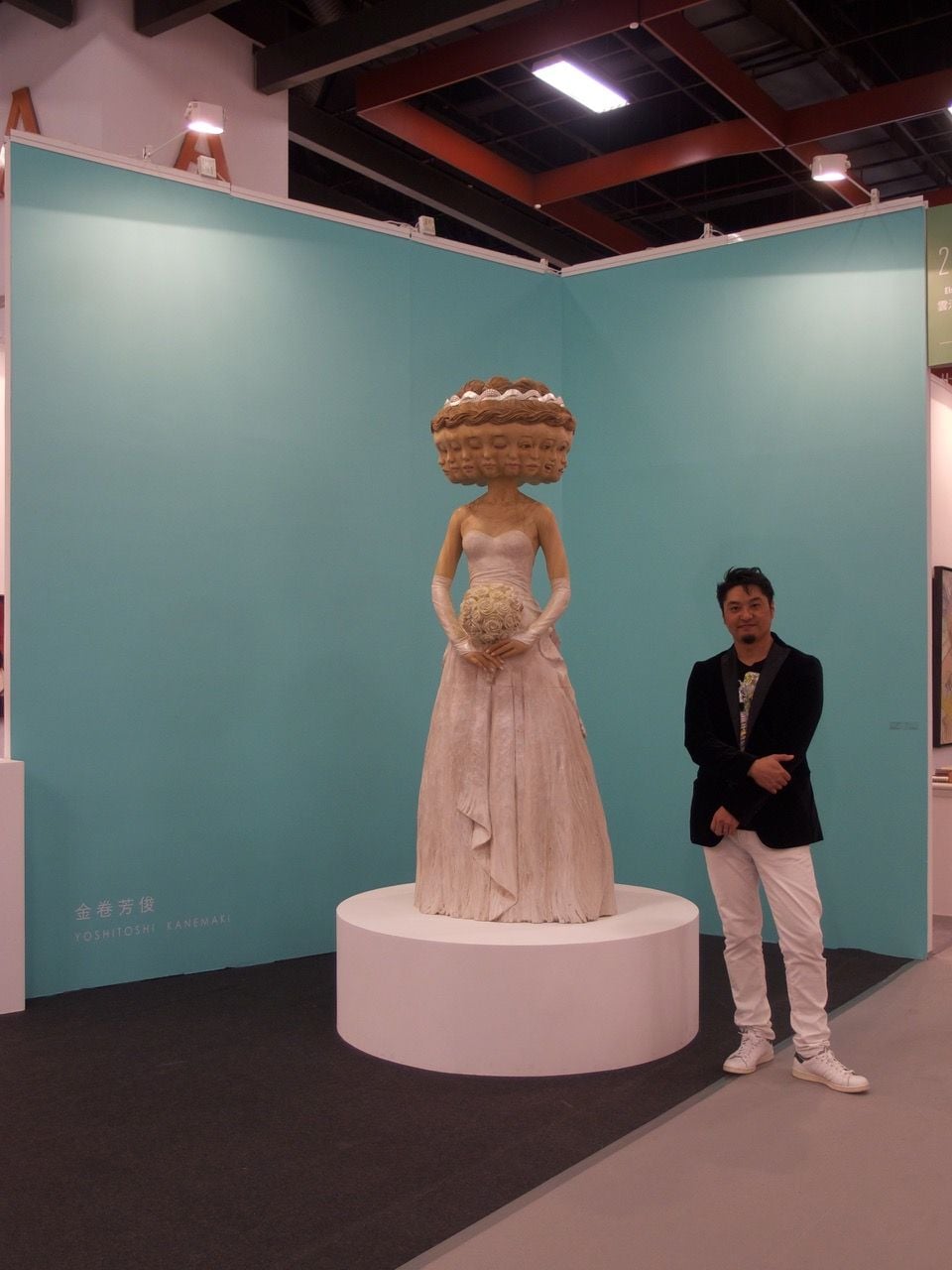 Artist Yoshitoshi Kanemaki stands next to one of his surreal hand-carved sculptures.