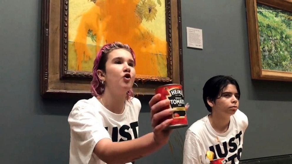 Two young Just Stop Oil activists defiantly throw a can of tomato soup on Van Gogh's 