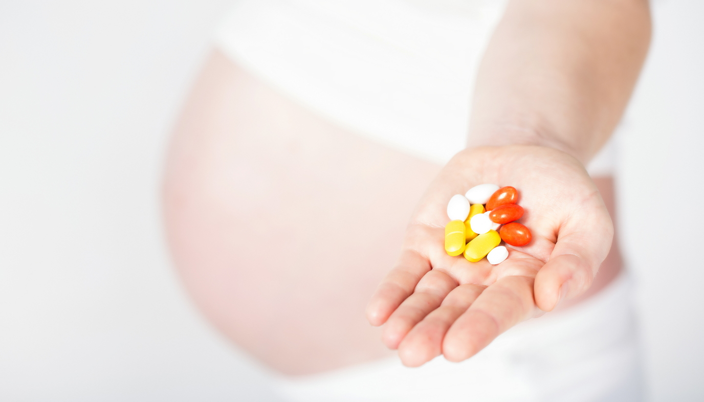 pregnant woman with a handful of vitamins